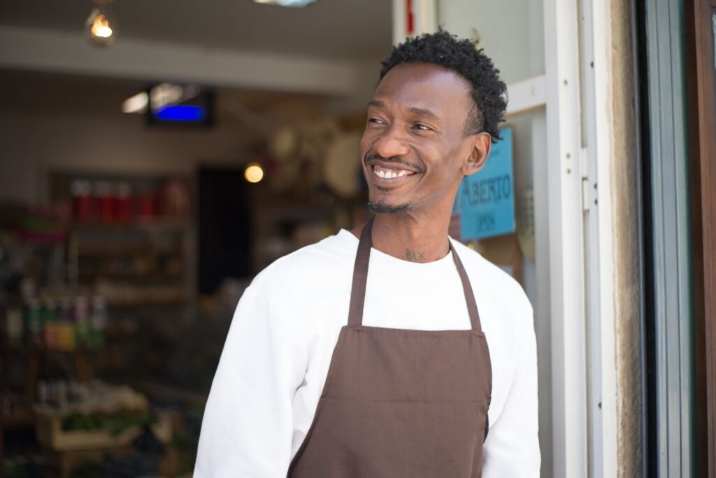 Commerçant souriant à l'entrée de son magasin